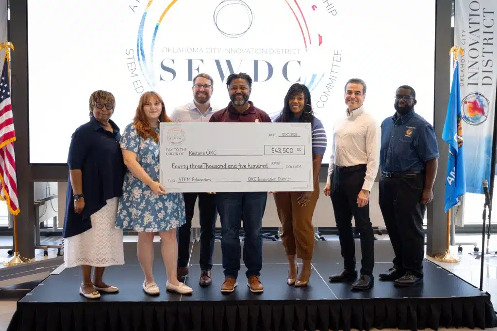 Grant recipients pose together with an oversized check in front of the OKCID STEM Education and Workforce Development Committee backdrop.