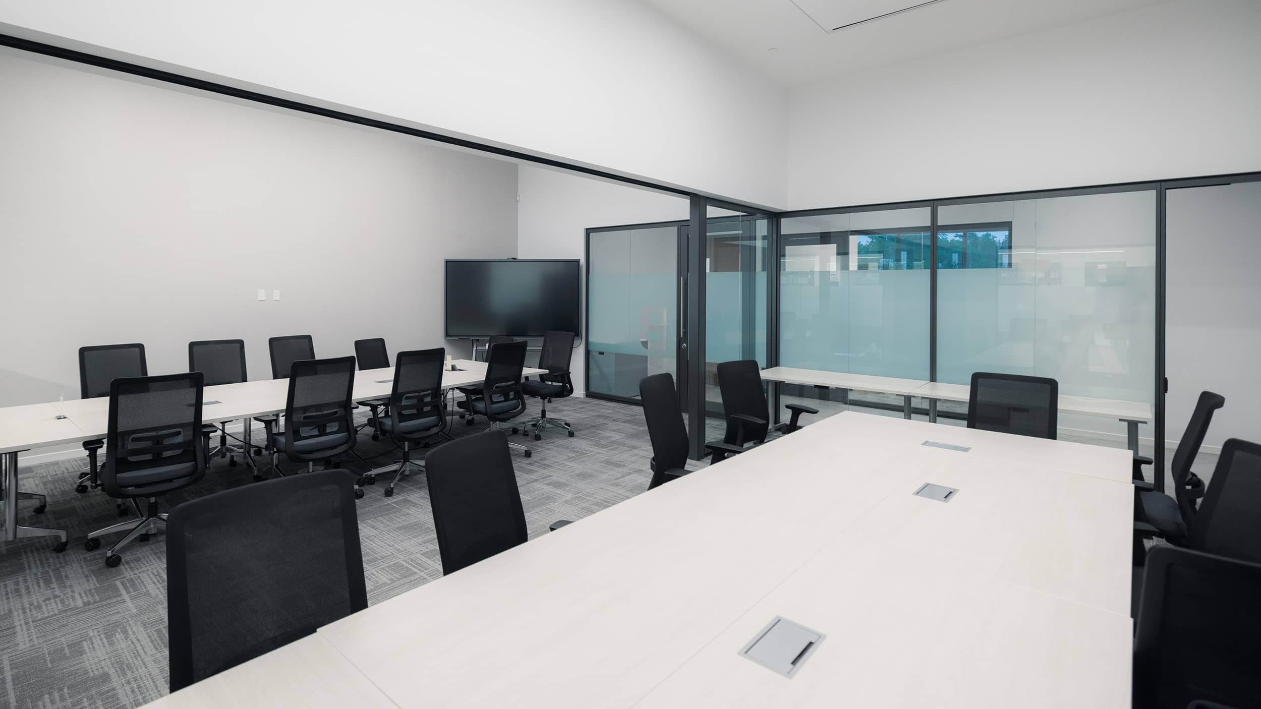 Innovation Hall meeting rooms with glass partitions, conference tables, rolling chairs, and monitors.